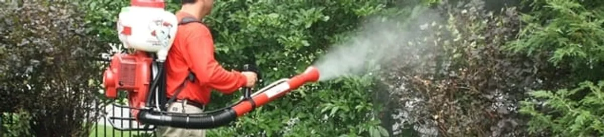 Mosquito control technician fogging shrubs and landscaping for mosquito treatment in Fort Wayne, IN