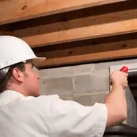 Termite inspection technician checking a basement wall and framing for termite activity in Fort Wayne, IN